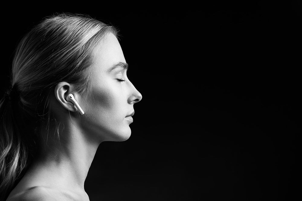 Black and white photo of a woman's face side view with wireless headphones