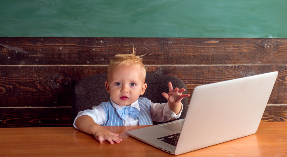 Photo of a toddler in a suit sitting at a table with a laptop computer|Close up photo of the side of a laptop computer, with an ethernet cable plugged into it