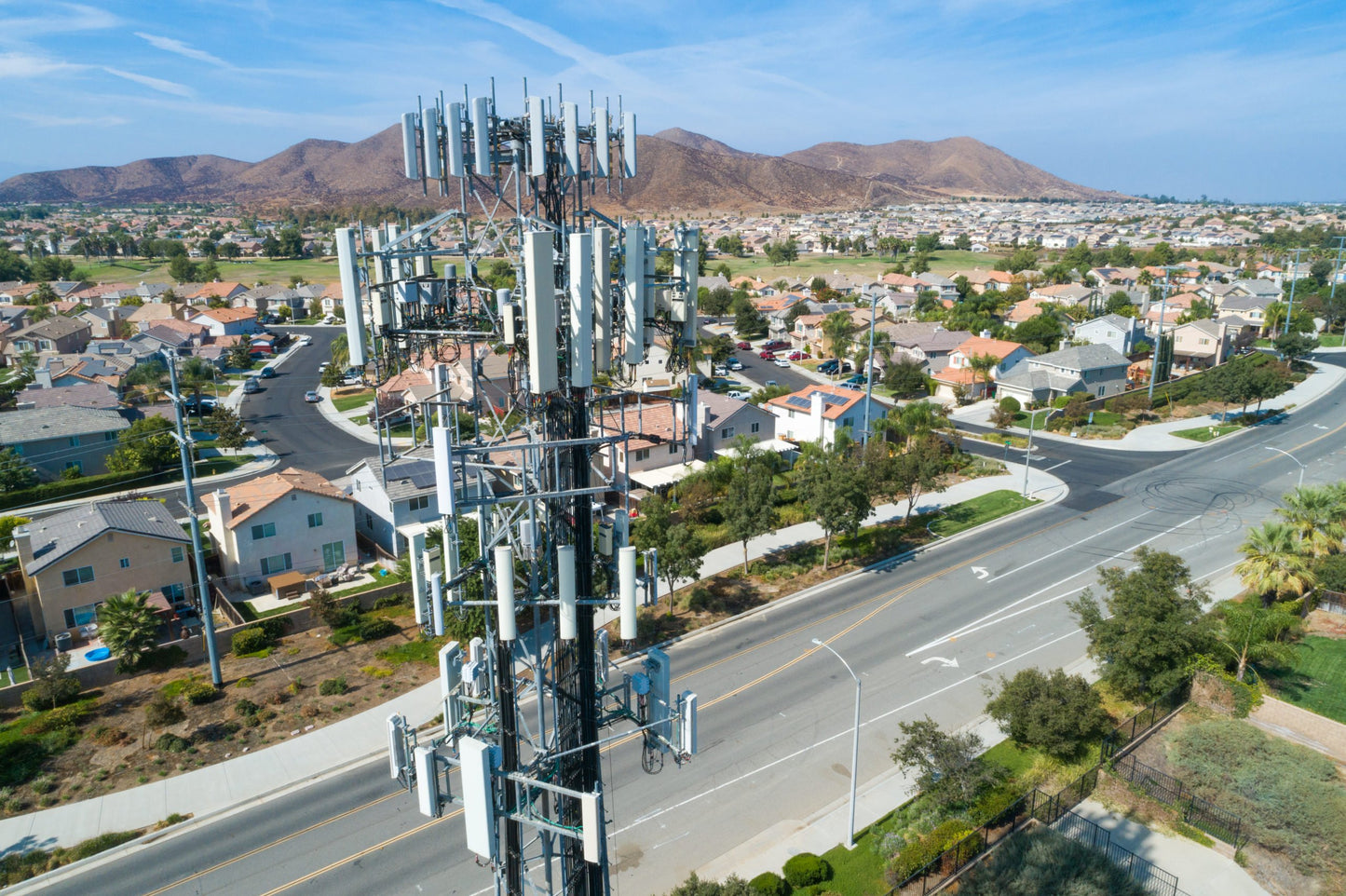 Photo of a 5G tower overlooking a populated suburban area|Photo of 5G antennas on top of a building
